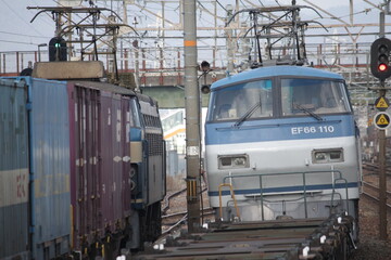 日本の線路で離合する2台の青い電気機関車と貨物列車