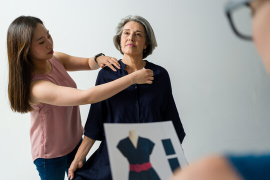 Fashion designers discussing dress prototype with senior model