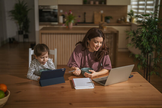 Mother and daughter using digital devices during breakfast at home
