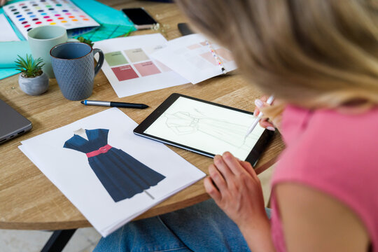 Fashion designer drawing dress on tablet in her office