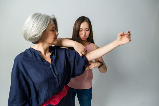Fashion designer adjusting sleeve of mature model's blouse