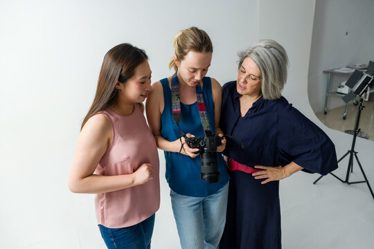 Photographer showing camera settings to assistants in photo studio
