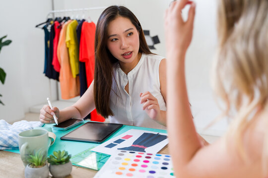 Designer showing fashion design sketches on tablet to client