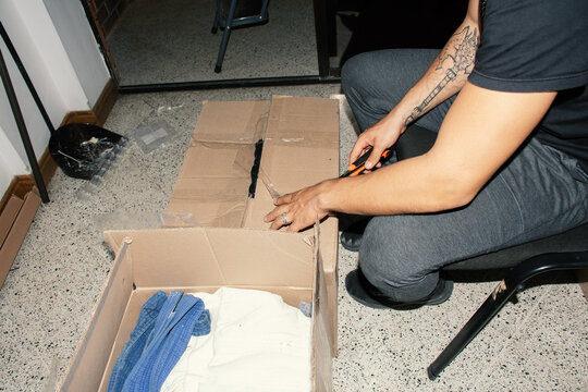 Person opening cardboard box with scissors in indoor space