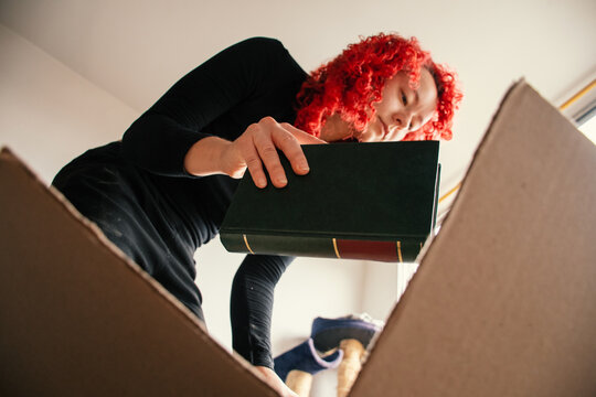 Woman examines a book before placing It in a cardboard box