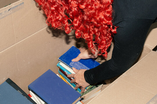 Organizing books in a cardboard box during a decluttering session
