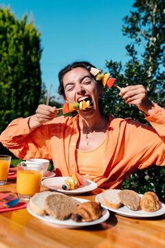 Young woman eating delicious fruit for breakfast outdoors