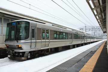 雪の積もった駅に止まる快速列車 © JtO