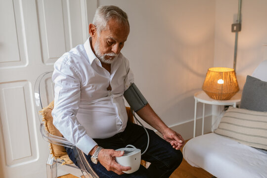 Elderly Man Measuring Blood Pressure at Home in a Cozy Setting