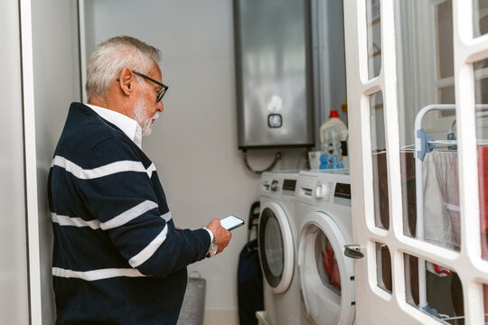 Man Using Smartphone While Clothes Washing