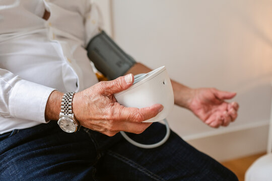 Elderly Man Measuring Blood Pressure in a Cozy Indoor Setting
