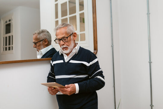 Old Man Reading Tablet in Modern Interior