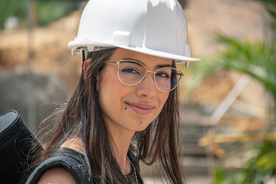 Young woman with a hard hat smiles at construction site