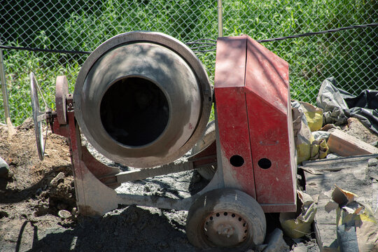 Concrete mixer on construction site surrounded by materials