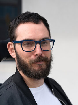 Man With Glasses and Beard Poses Against a Neutral Background
