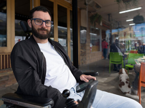 Man in Wheelchair Enjoys Time at Cafe With Dog Nearby