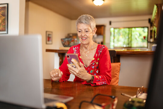 Senior woman using her phone in front of computer