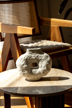 Rustic papier-mache vase on a round table in natural sunlight