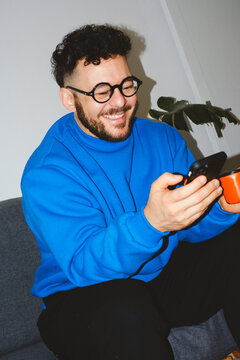 Man Smiling at Phone with Coffee Cup