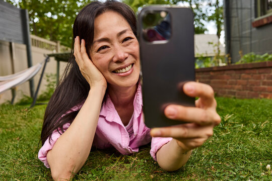 Asian woman laying down looking at her phone 