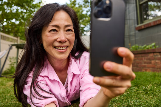 Asian woman laying down looking at her phone 
