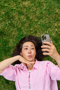 Middle aged asian woman taking selfies on grass outside