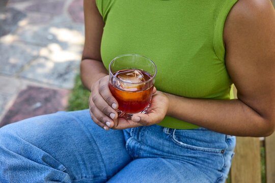 Young woman drinking a cocktail sitting on the grass
