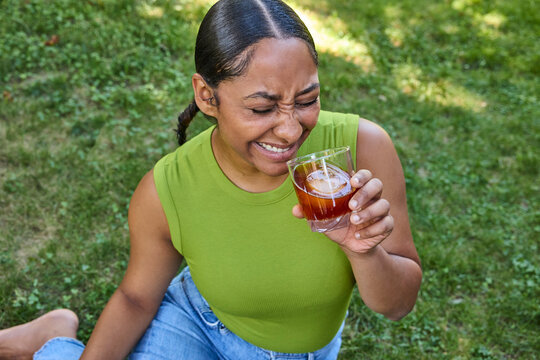 Young woman drinking a cocktail sitting on the grass