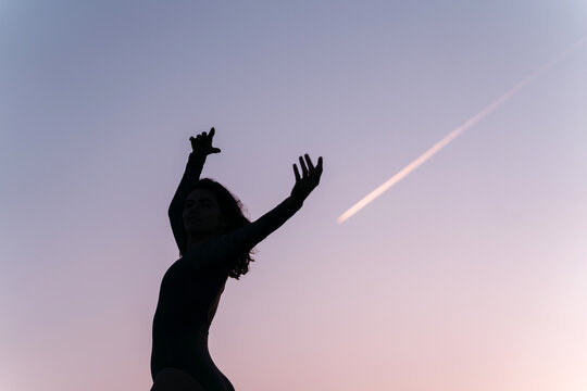 Woman dancing at dusk with contrail that resembles shooting star