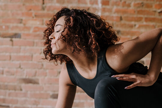 Woman Stretching Against Brick Wall