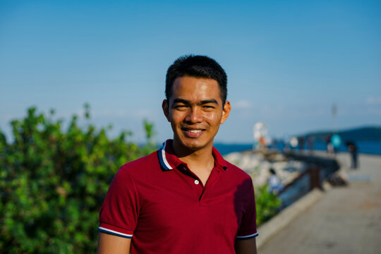 Young Man smiling while standing on the waterfront platform at sunset