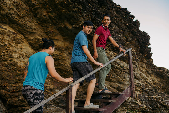 Friends walking on the stairs near the rocky coast at sunset