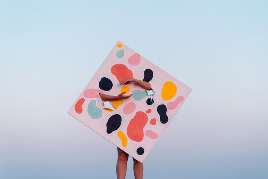 Hands Reaching out From a Colorful Abstract Art Canvas