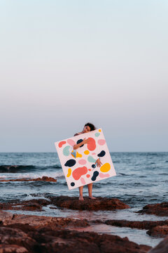 Artist Holding Colorful Abstract Art Canvas by the Sea