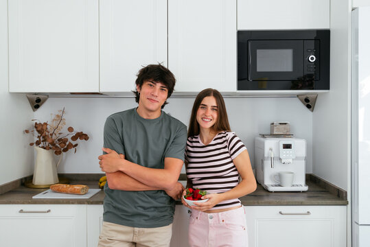Cool roommates enjoying fresh strawberries in a bright kitchen


