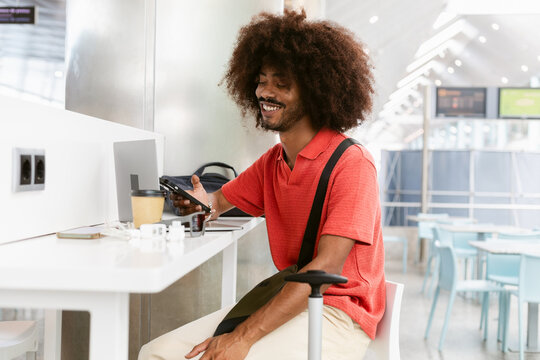 Smiling Man Enjoying Coffee While Using Smartphone at Cafe