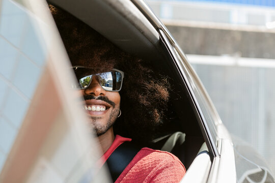 Man With Sunglasses Smiling From Car Window on Sunny Day
