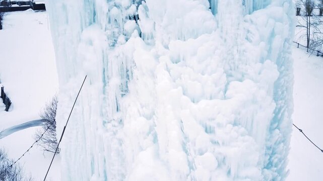 A frozen water tower. The water has turned to ice. It's abnormally cold. An ice-covered iron structure that holds water. An ice-covered iron water tower.