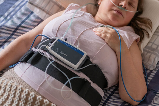 Patient undergoing clinical sleep study diagnostic sensors, woman sleeping with nasal cannula and pulse oximeter, medical monitoring apnea device, screening and treatment chronic sleep deprivation