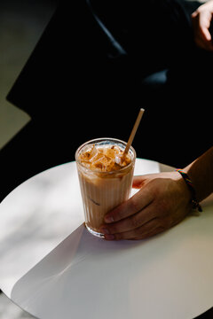 Unidentified hand lifting and tasting a chai latte beverage