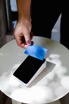 Close-up of a hand holding a contactless card to authorize a payment