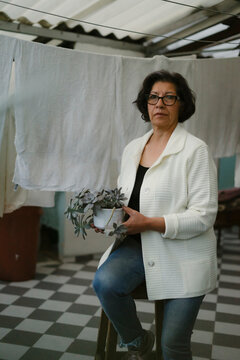 Senior woman holding plant sitting in laundry room