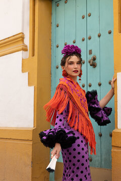 Festive portrait of woman in flamenco dress near colorful building