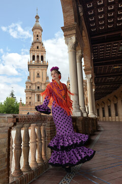 Woman in purple polka dot flamenco dress posing at a historic building