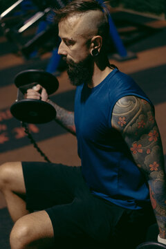 Athletic tattooed male exercising under streetlights