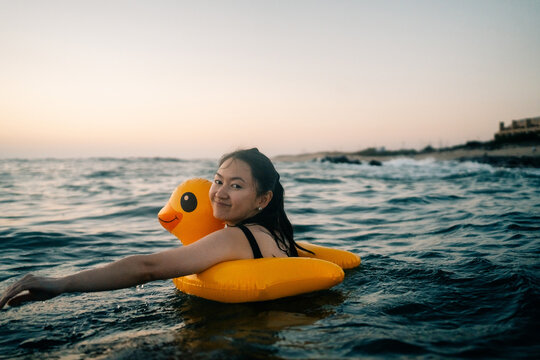 Enjoying a Sunset Swim With a Yellow Duck Float in the Ocean