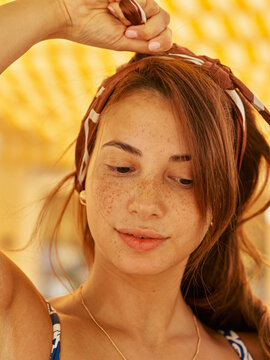 Young Woman Adjusts Headband Under Bright Canopy While Smiling