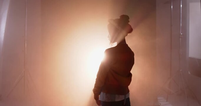 On sequence start model is lowering and raising hand as backlight is creating halo silhouette