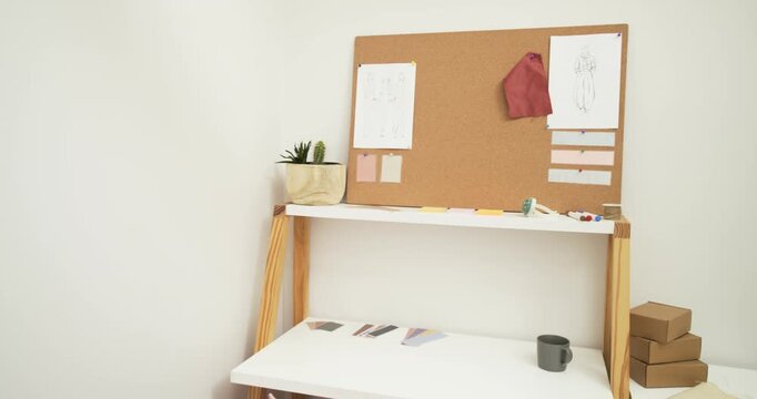 Camera starting pan revealing workspace with clothing rack sliding away and desk area appearing