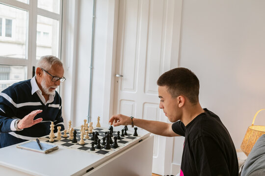 Elderly Man Teaches Young Player Strategic Moves in Chess Game